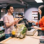 Latin customer at the counter holds their mobile phone up to the terminal to pay-cm