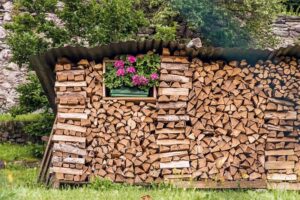 Beautiful woodpile and decorative pink flowers vase in italian mountain village-cm
